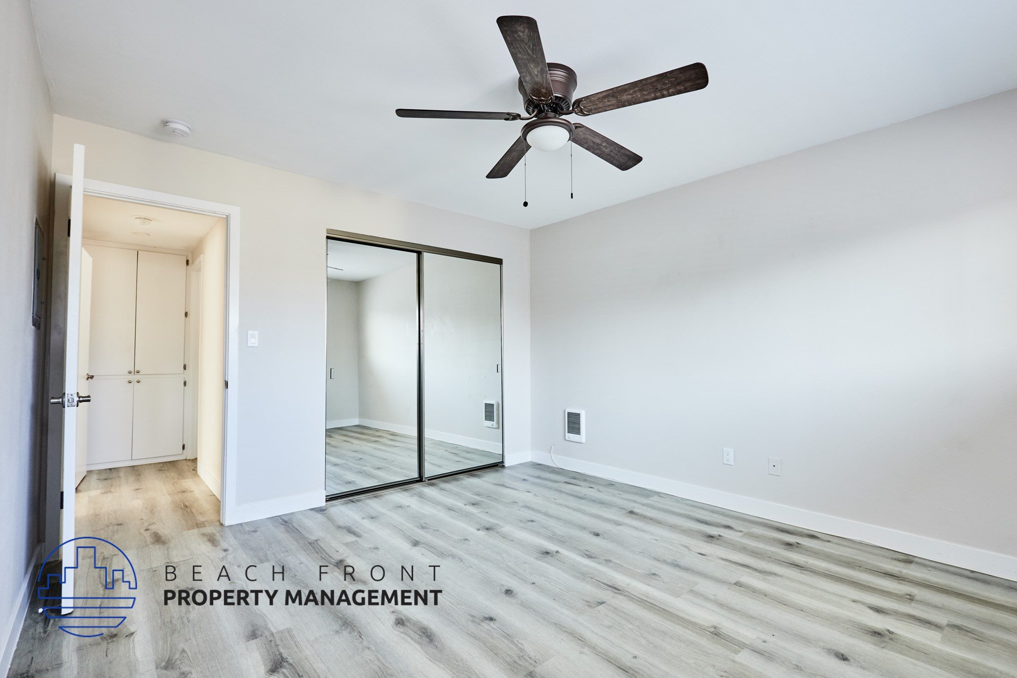A room with a ceiling fan and wooden flooring.